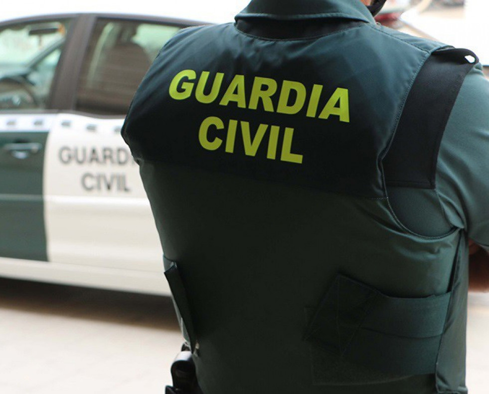 Archivo - Un agente de la Guardia Civil, de espaldas, junto a un vehículo oficial. Imagen de archivo