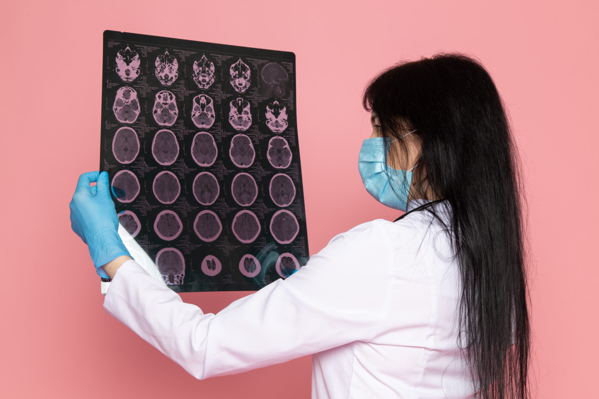 Young woman white medical suit blue gloves blue protective mask with stethoscope pink