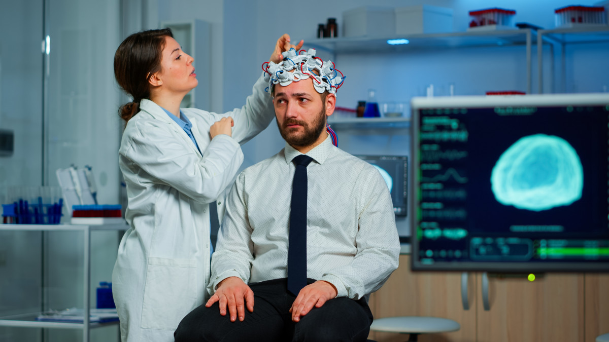 Patient with brain scan discussing with researcher neurological doctor while adjusting brainwave scanning headset examining diagnosis disease explaning eeg results health status brain functions