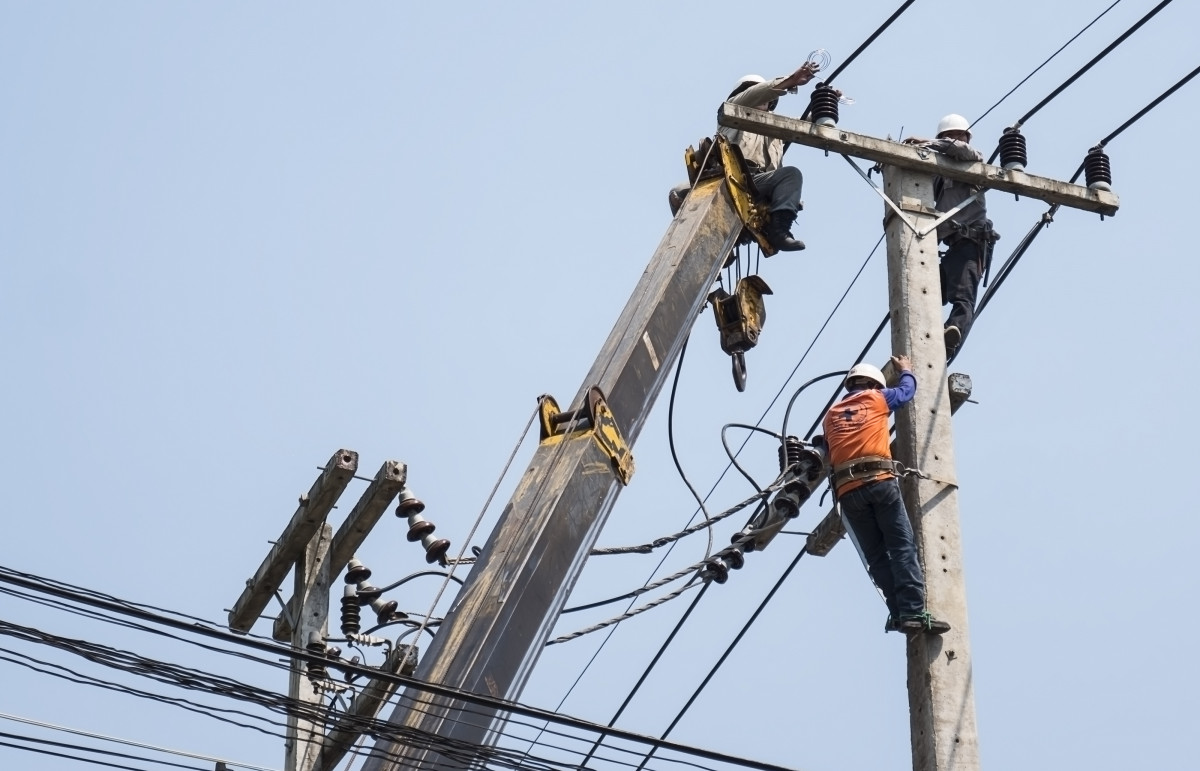 Selective focus electricians are fixing power transmission line electricity pole