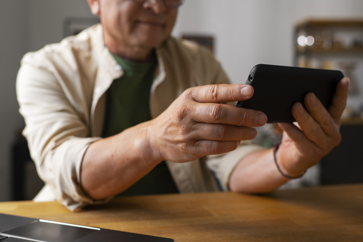 Retrato de un hombre mayor que usa un telefono inteligente en casa