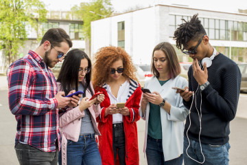 Grupo de amigos modernos usando el telefono celular al aire libre