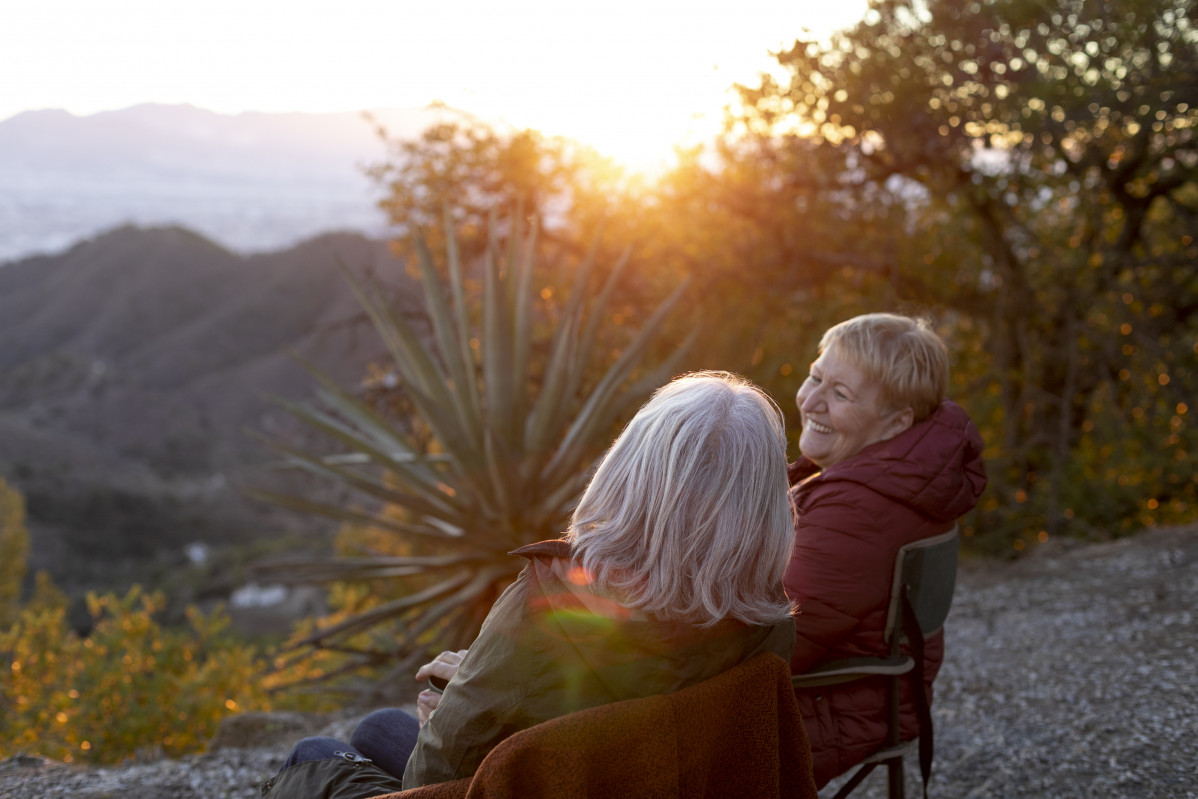 Dos mujeres mayores en una escapada la naturaleza sentadas en sillas y disfrutando de su tiempo