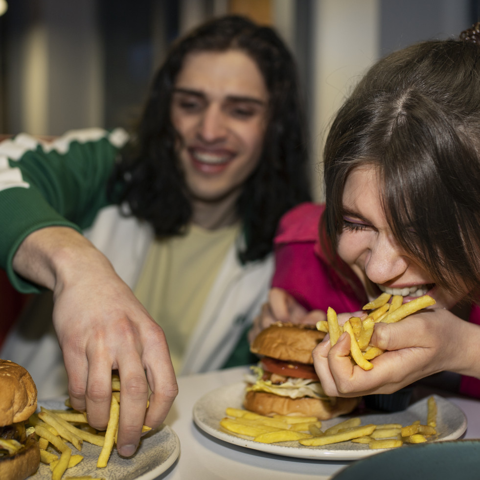 Amigos de tiro medio comiendo comida rapida de una manera divertida
